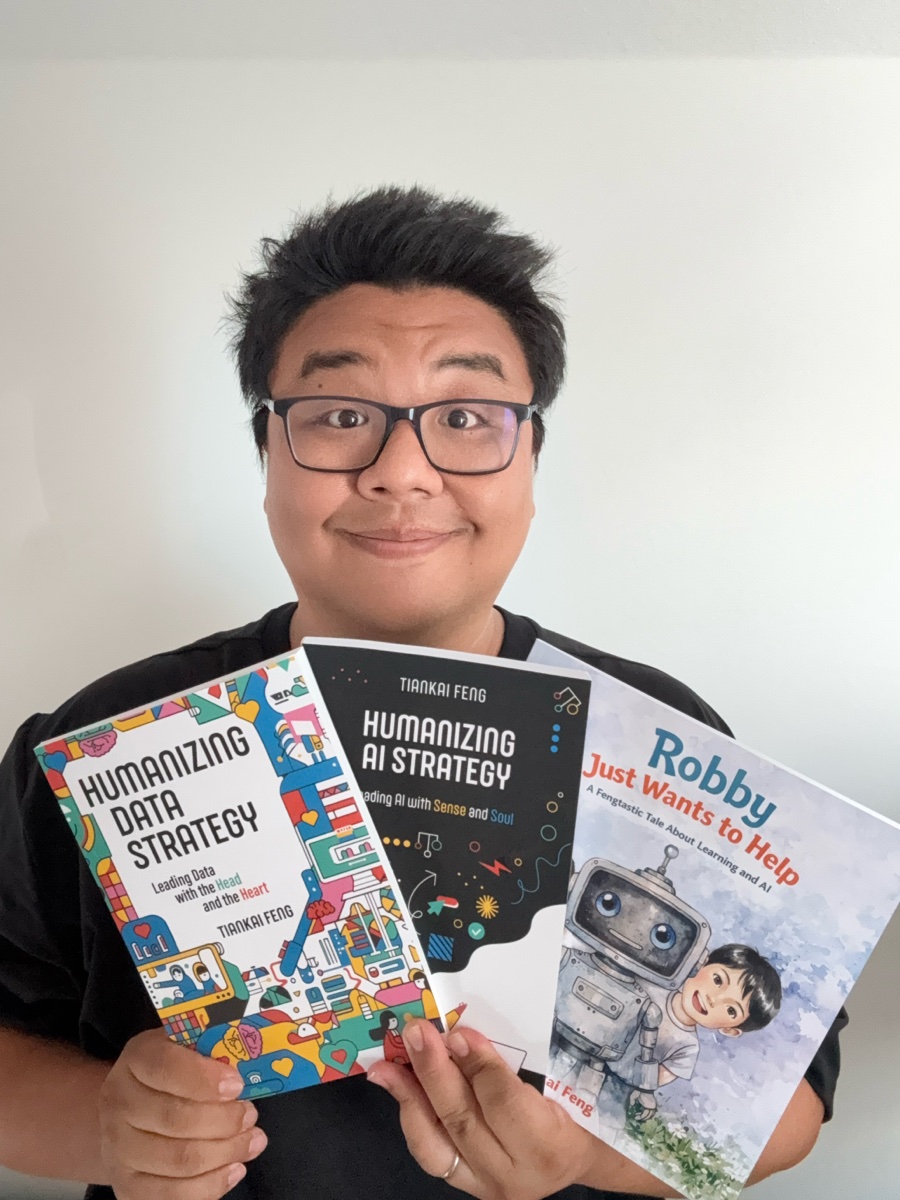 Tiankai Feng holding all three of his books: Humanizing Data Strategy, Humanizing AI Strategy, and Robby Just Wants to Help