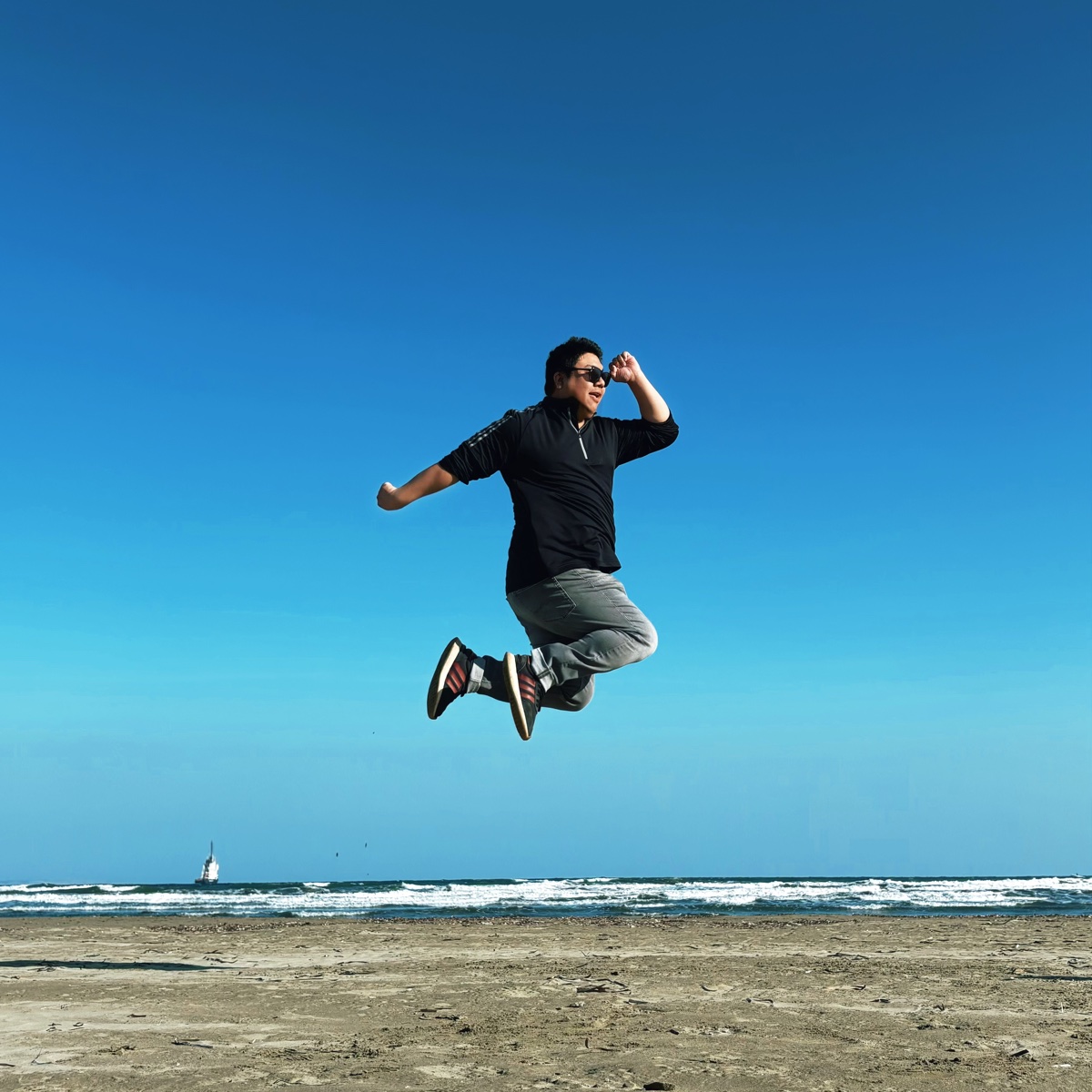Tiankai Feng jumping for joy on a beach